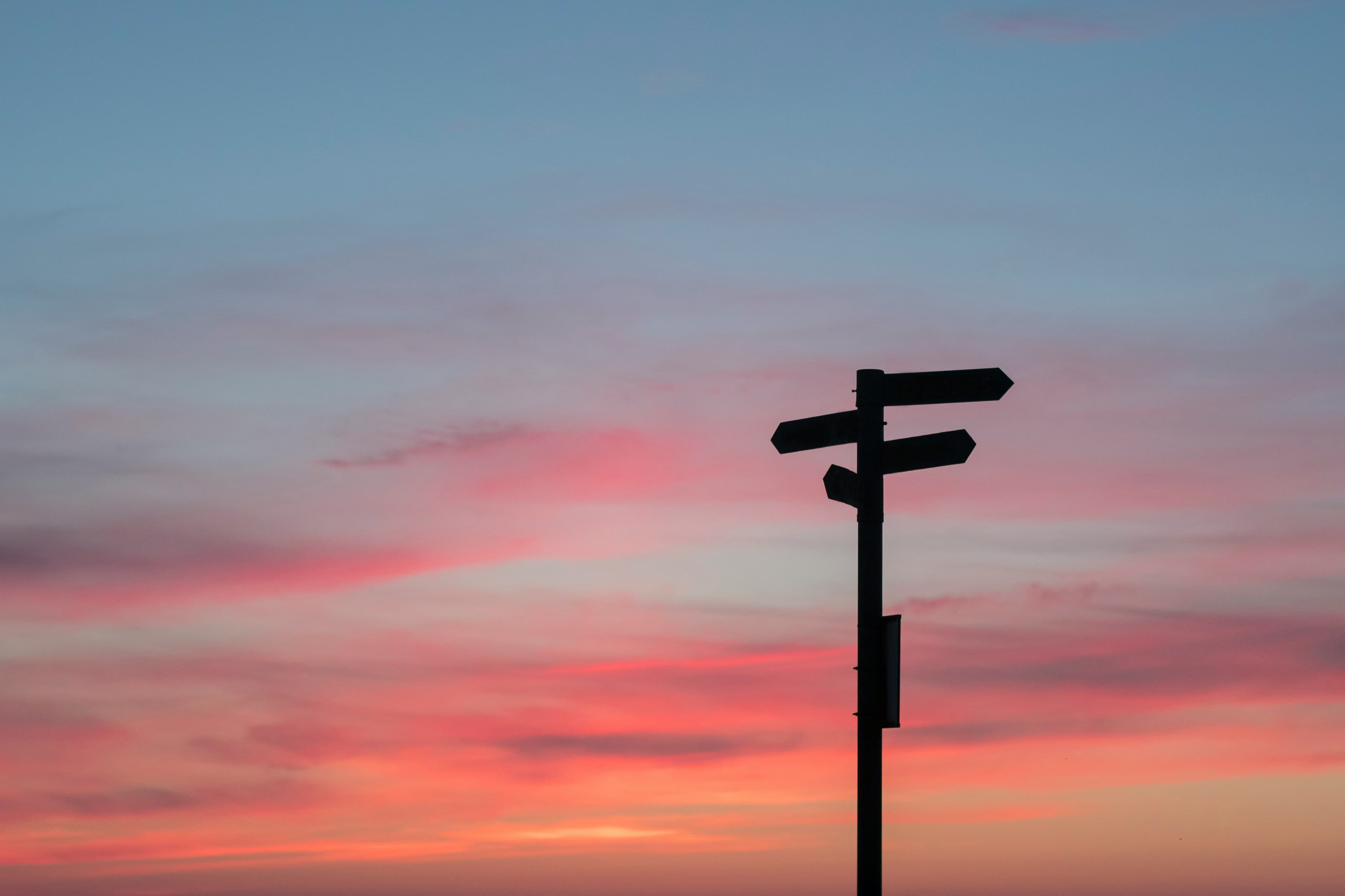 Wegweiser vor farbigem Abendhimmel